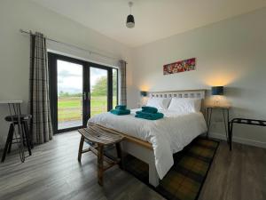 sypialnia z dużym łóżkiem i dużym oknem w obiekcie Willow Lodge w mieście Muir of Ord