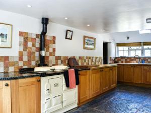 a kitchen with wooden cabinets and a stove top oven at Plum Tree Cottage in Trent
