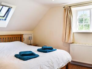 a bedroom with two blue towels on a bed at Plum Tree Cottage in Trent