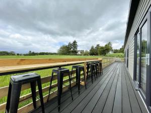 a row of stools on a deck with a field at Willow Lodge in Muir of Ord