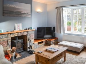 a living room with a fireplace and a tv at Bramble Cottage in Craster
