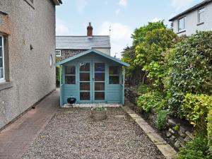 a blue shed sitting outside of a house at Bramble Cottage in Craster