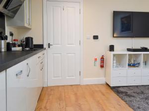 a kitchen with white cabinets and a white door at The Hideaway in Sheringham