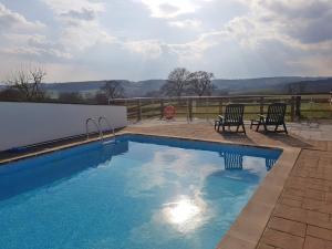 a swimming pool with two chairs next to a fence at Old Orchard Barn - The Annexe in Buckland St Mary