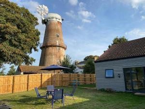 a lighthouse with a table and chairs in a yard at Mill View in Hickling