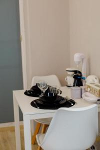 einen weißen Tisch mit Teller und Gläsern darauf in der Unterkunft Rooms in Yard in Kórinthos