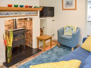 a living room with a fireplace and a blue chair at Willow Cottage in Ludham