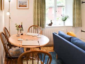 a dining room with a table and a blue couch at Willow Cottage in Ludham