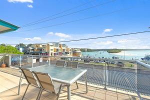 een tafel en stoelen op een balkon met uitzicht op het water bij Jervis Bay Vista in Huskisson