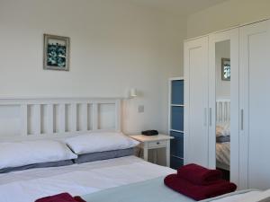 a white bedroom with two beds and a mirror at The Stables in Torbeg