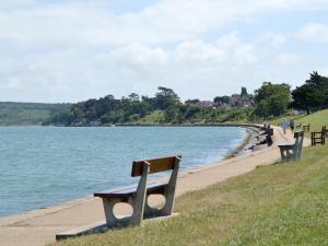 a row of benches on a path next to a body of water at Solent Cottage - Pqqu in Yarmouth
