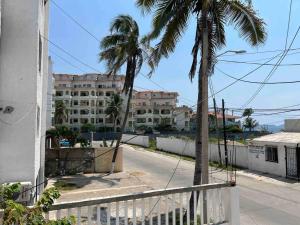 eine leere Straße mit Palmen und einem Gebäude in der Unterkunft Departamento Todo Cerca Playa Azul in Manzanillo
