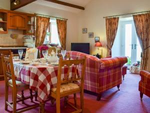 a dining room with a table and a couch at Rambling Rose- Lwg in Ireby