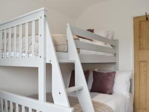 a white bunk bed in a white room with a staircase at Sapphire Cottage in Pakefield