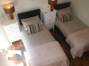 a bedroom with two beds and a white dresser at Baileys Barn in Bonsall