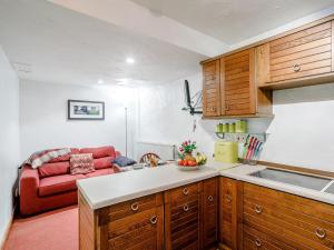 a kitchen with wooden cabinets and a red couch at The Hayloft in Glossop