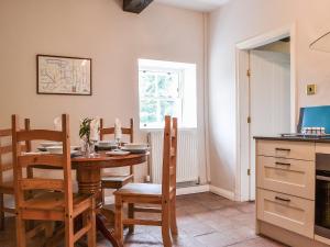 cocina con mesa, sillas y ventana en Jenkin Lodge, en Braithwaite