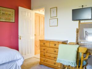 um quarto com uma cama, uma cómoda e uma televisão em Brighton House em Nairn