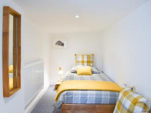 a bedroom with a bed with a yellow blanket at The Old Sunday School in Taxal