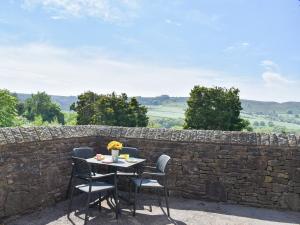 a table and chairs on a patio with a stone wall at The Old Sunday School in Taxal