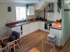 a kitchen with white cabinets and a wooden floor at Macrury Cottage in Paible