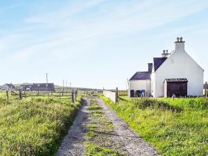 an old farm house and a dirt road at Macrury Cottage in Paible