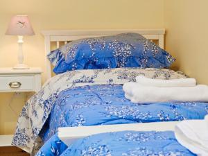 a blue bed with blue and white sheets and pillows at Clogwyn Bach in Trevor