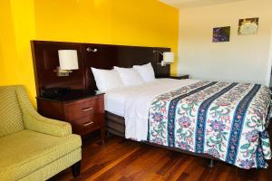 Cambridge Inn في مدينة اوكلاهوما: سرير في غرفة مع كرسي وسيدكس السرير سيدكس
