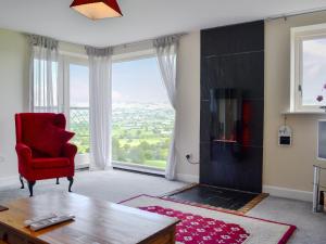 a living room with a red chair and a large window at Oak House in Rhewl
