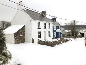 a white house with a blue door in the snow at Stephens Cottage in Llangwm