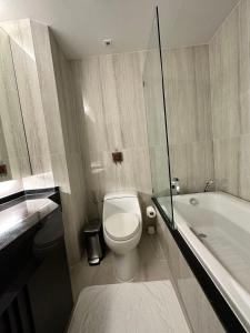a bathroom with a white toilet and a bath tub at Erawan condo in Chiang Mai