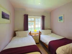 two beds in a room with a window at Drovers in Lanteglos