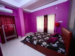 um quarto com paredes roxas e uma cama num quarto em Veda Homestay em Agartala