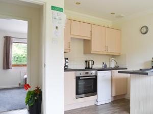 a kitchen with white cabinets and a stove top oven at Rivendell Cottage in Fort Augustus