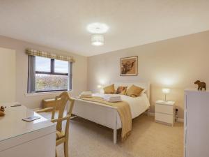 a bedroom with a bed and a desk and a window at Rowan Muir in Springside