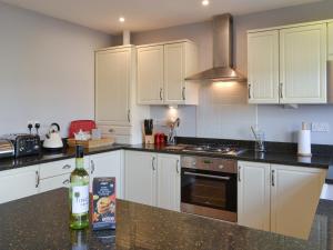 a kitchen with white cabinets and a bottle of wine on a counter at Wagtail Cottage in Lesbury