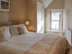 a bedroom with a large bed and a window at Wagtail Cottage in Lesbury