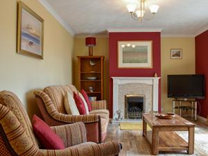 a living room with two chairs and a fireplace at Anchorage Cottage in Lamlash