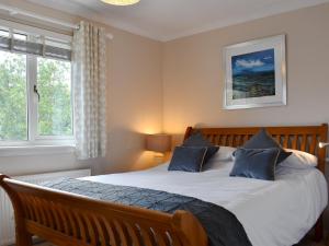 a bedroom with a large bed with blue pillows at Anchorage Cottage in Lamlash