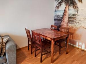 a dining room table with chairs and a palm tree mural at Kaukajärven Joutsen - valoisa ja tilava kaksio in Tampere