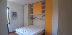 a small room with a small bed with yellow cabinets at Stintino - Cala Lupo in Stintino
