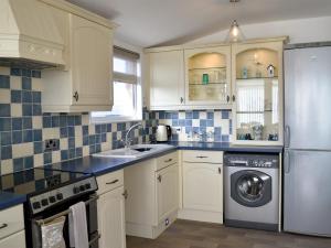 eine Küche mit weißen Schränken, einer Waschmaschine und einem Trockner in der Unterkunft Coles Retreat in Anderby