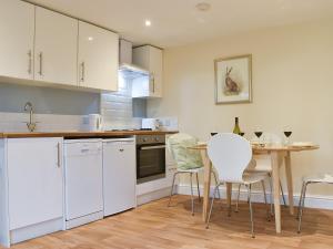 a kitchen with white cabinets and a table with chairs at Delamere House- The Snug in Scagglethorpe