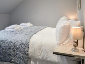een bed met witte kussens en een tafel met een lamp bij Donallan in Palnure