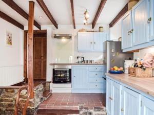 a kitchen with blue cabinets and a brick floor at Ty Lewis Cottage in Llanelli