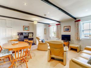 a living room with a table and chairs and a tv at Dovecoat Cottage in Embleton