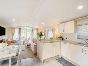 a kitchen with white cabinets and a living room at Ochil View Lodge in Dollar