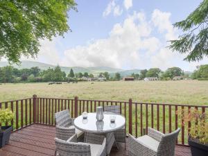 a table and chairs on a deck with a field at Ochil View Lodge in Dollar