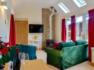 a living room with a green couch and red curtains at The Old Inverchroskie Kennels in Enochdhu