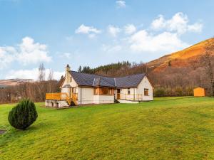 a house in a field with a hill in the background at Bidean Lodge in Glencoe